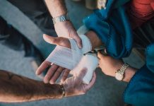 Understanding Comparative Fault In Florida Personal Injury Cases Close-up of two people bandaging an injured hand outdoors, focusing on first aid care.