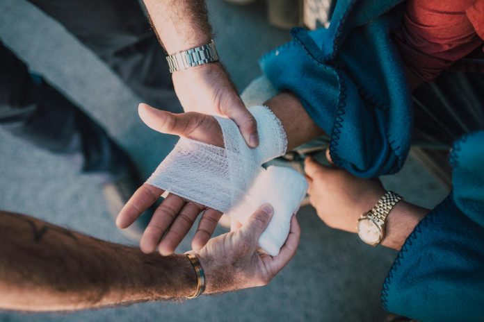 Photo by RDNE Stock project Close-up of two people bandaging an injured hand outdoors, focusing on first aid care.