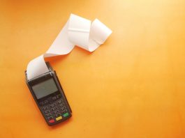 Cutting Unnecessary Expenses a cell phone sitting on top of a table next to a roll of paper