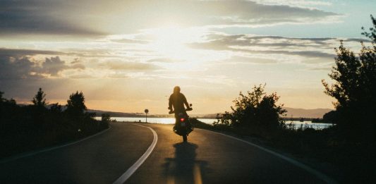 Maximizing Compensation After a Motorcycle Accident: New York Legal Strategies Silhouette of a motorcyclist riding on a scenic road during a beautiful sunset, emphasizing freedom and adventure.