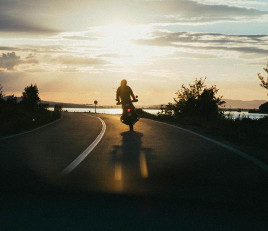 Maximizing Compensation After a Motorcycle Accident: New York Legal Strategies Silhouette of a motorcyclist riding on a scenic road during a beautiful sunset, emphasizing freedom and adventure.
