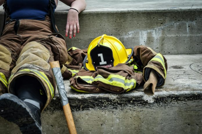 Photo by Pixabay Firewoman taking a break on concrete steps with gear and helmet nearby.