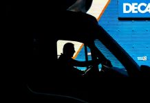 Can You Sue a Trucking Company for Driver Error? Silhouette of a driver in a vehicle with a blue industrial backdrop, illustrating transportation.
