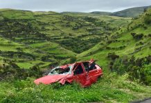 What Evidence Is Crucial In An Everett Car Accident Case A red wrecked car lies abandoned in a scenic green valley, highlighting rural decay.