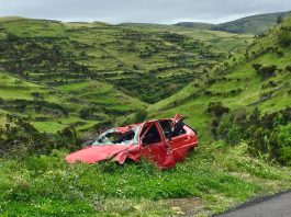 What Evidence Is Crucial In An Everett Car Accident Case A red wrecked car lies abandoned in a scenic green valley, highlighting rural decay.