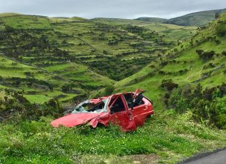 What Evidence Is Crucial In An Everett Car Accident Case A red wrecked car lies abandoned in a scenic green valley, highlighting rural decay.