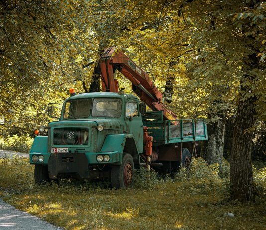 Why Industrial Tools and Vehicles Age Faster Than They Should An old truck with a crane sits among the trees.