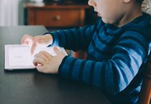 Struggling to Limit Your Child’s Screen Time? Try This Instead boy sitting on chair beside table using tablet computer