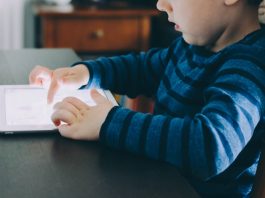 Struggling to Limit Your Child’s Screen Time? Try This Instead boy sitting on chair beside table using tablet computer