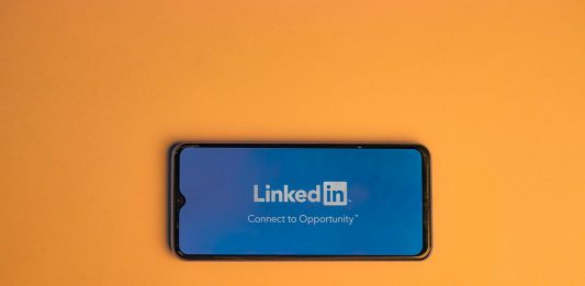 How to Choose the Best Automation Software for LinkedIn? Smartphone showing LinkedIn login on vibrant orange background, symbolizing connectivity.