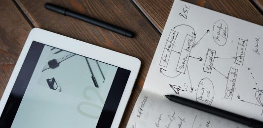 Gear Up Your Game, Promote Your Name with Totally Branded Digital and handwritten brainstorming tools on a wooden desk, ideal for business and study contexts.