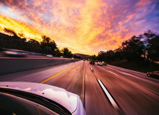 Using a Car Accident Settlement Calculator the Right Way Motion blur of cars speeding on an Irvine highway at sunset with vibrant skies.