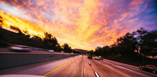 Using a Car Accident Settlement Calculator the Right Way Motion blur of cars speeding on an Irvine highway at sunset with vibrant skies.