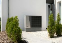 Why Your Future HVAC Might Come With a Subscription Plan Outdoor air conditioner unit on a modern building surrounded by greenery and landscaping.