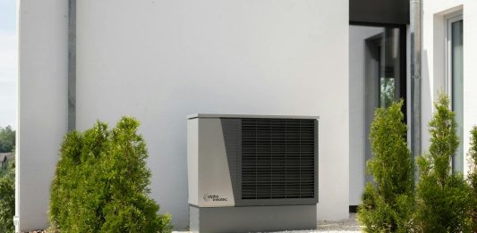 Why Your Future HVAC Might Come With a Subscription Plan Outdoor air conditioner unit on a modern building surrounded by greenery and landscaping.