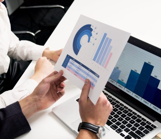 The Surprising Link Between MRO Data Quality and Worker Safety Business professionals discussing data charts and graphs in a modern office setting.
