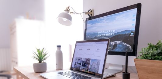 Hybrid Work Tech Essentials 2026: Build a Setup That Works MacBook Pro on table beside white iMac and Magic Mouse
