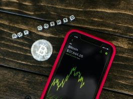 You Should Know About 5 Changes in Crypto Regulations Smartphone showing bitcoin price with a physical coin and text representing cryptocurrency investment.