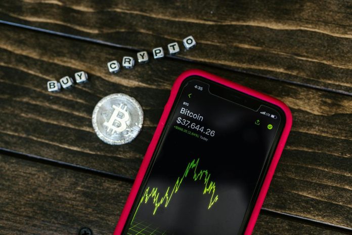 Photo by RDNE Stock project Smartphone showing bitcoin price with a physical coin and text representing cryptocurrency investment.