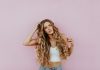How Blonde Tape-In Hair Extensions Can Transform Your Look Instantly woman standing next to pink wall while scratching her head