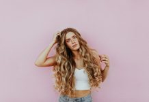 How Blonde Tape-In Hair Extensions Can Transform Your Look Instantly woman standing next to pink wall while scratching her head