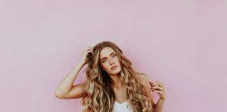 How Blonde Tape-In Hair Extensions Can Transform Your Look Instantly woman standing next to pink wall while scratching her head