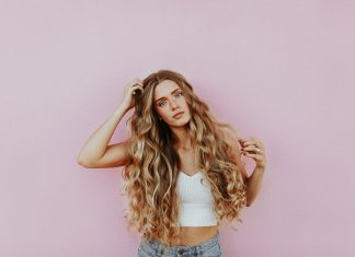 How Blonde Tape-In Hair Extensions Can Transform Your Look Instantly woman standing next to pink wall while scratching her head