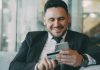 The Shift Toward Automated Financial Documentation in Modern Businesses Man in suit smiling while holding phone and credit card