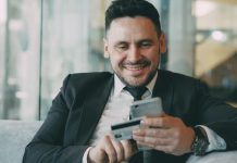 The Shift Toward Automated Financial Documentation in Modern Businesses Man in suit smiling while holding phone and credit card
