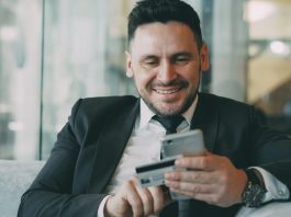 The Shift Toward Automated Financial Documentation in Modern Businesses Man in suit smiling while holding phone and credit card