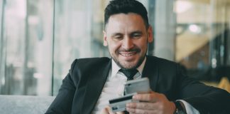 The Shift Toward Automated Financial Documentation in Modern Businesses Man in suit smiling while holding phone and credit card