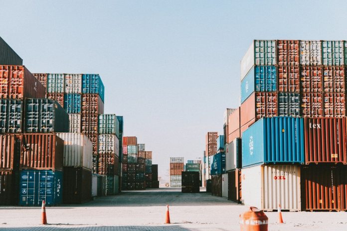 Photo by Fejuz a large amount of containers are stacked on top of each other