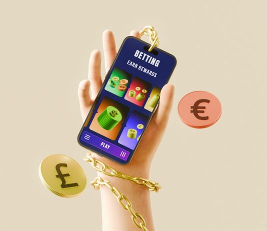 Why Betting Feels Better With The Right App Hand holding phone with betting app, currency, and gold chain.
