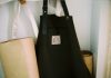 Look the Part: Why Personalised Aprons are Essential for Food and Hospitality Brands a black bag sitting on top of a shelf next to a lamp