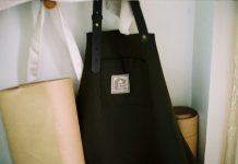 Look the Part: Why Personalised Aprons are Essential for Food and Hospitality Brands a black bag sitting on top of a shelf next to a lamp