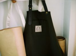 Look the Part: Why Personalised Aprons are Essential for Food and Hospitality Brands a black bag sitting on top of a shelf next to a lamp