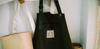 Look the Part: Why Personalised Aprons are Essential for Food and Hospitality Brands a black bag sitting on top of a shelf next to a lamp