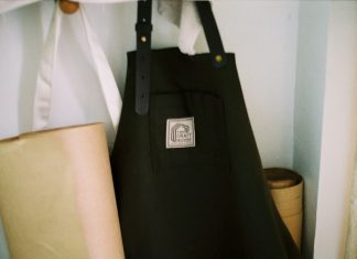 Look the Part: Why Personalised Aprons are Essential for Food and Hospitality Brands a black bag sitting on top of a shelf next to a lamp